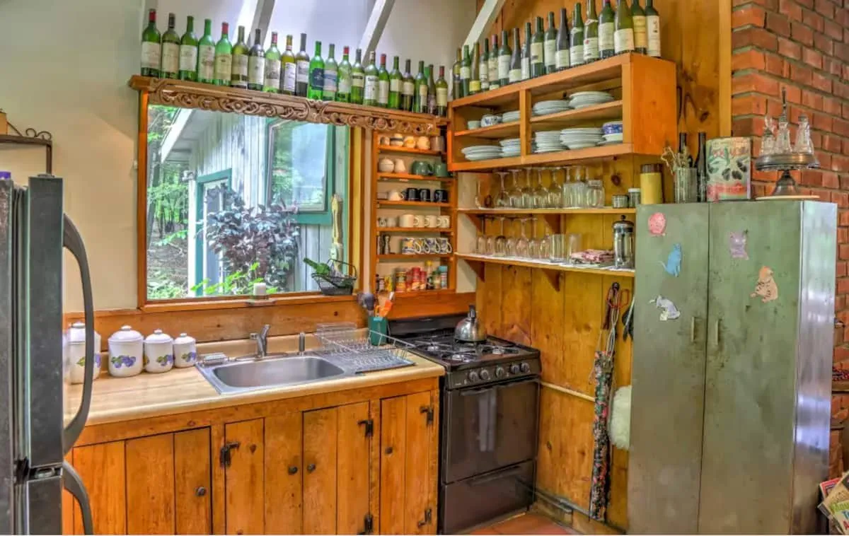 Pine kitchen with wine bottles lined along a high shelf.