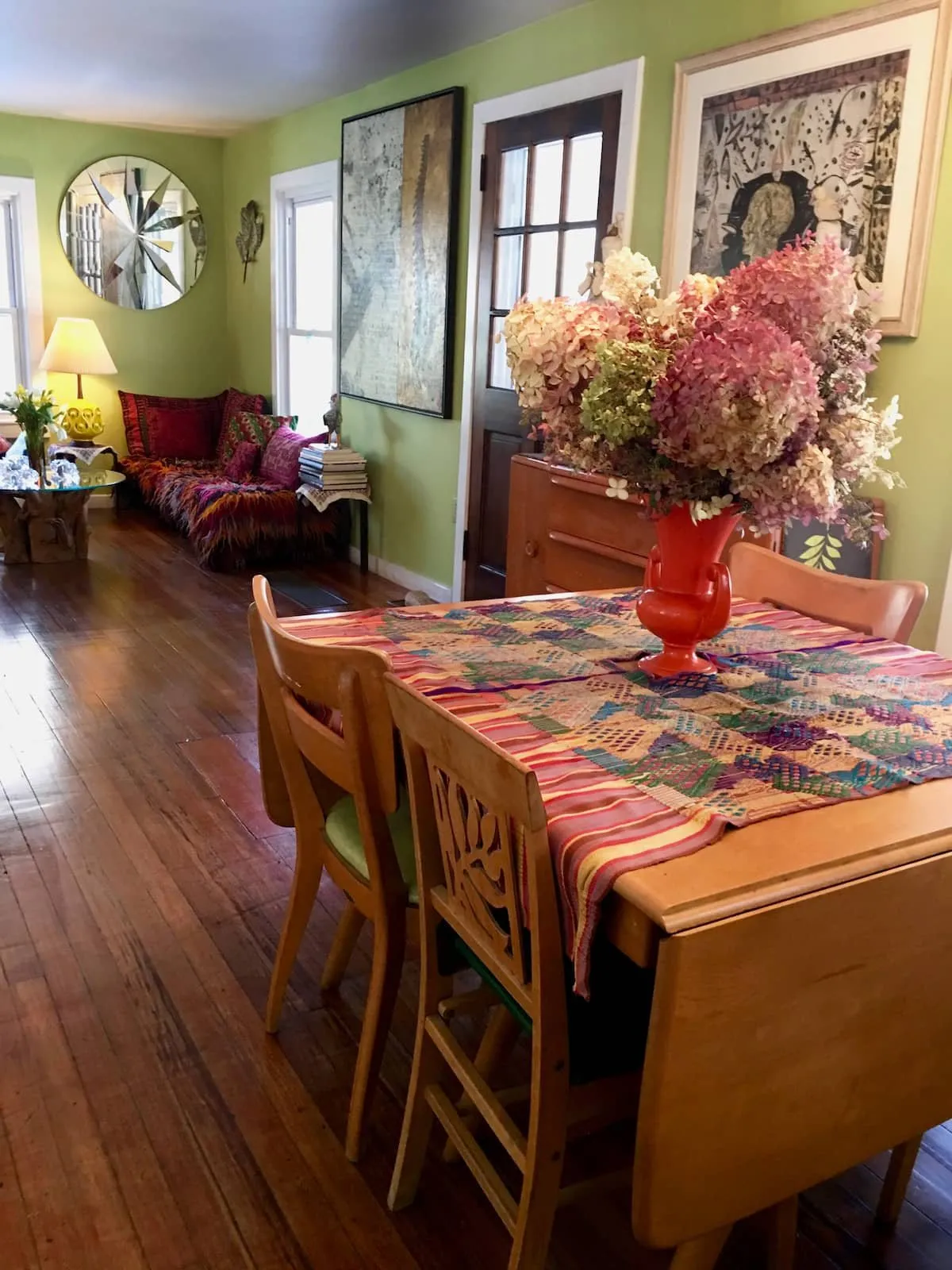 Dining table set under a window in a green-walled cottage room.