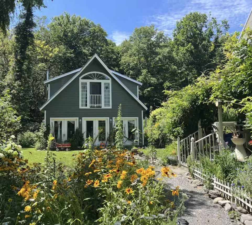 Green gabled cottage behind a bed of black-eyed susans.