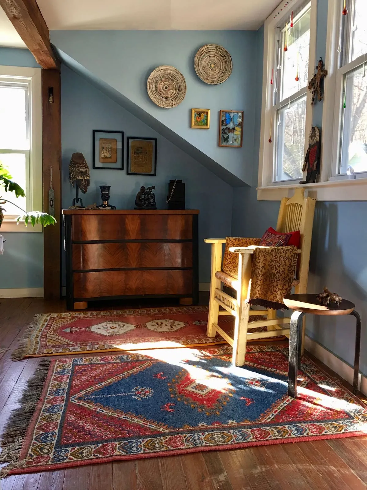 Sunlit room with a ladderback rocking chair on a red patterned rug.