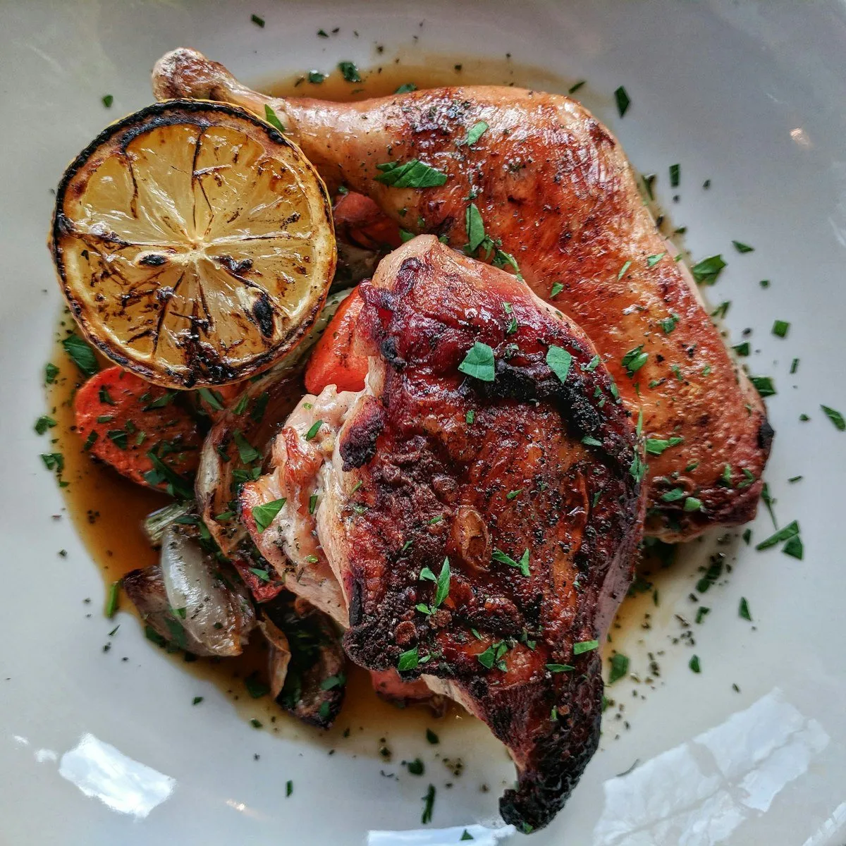 Roast chicken with a charred half lemon.
