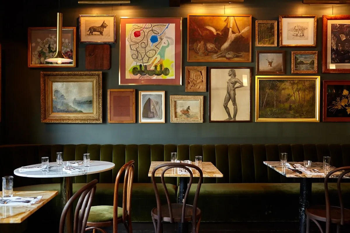 Silvia’s dining room, banquette seating below a wall hung salon-style with art.